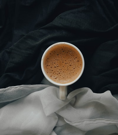 white ceramic mug on white textile